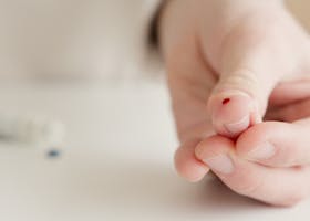 Close-up of a hand with a finger prick for home blood testing. Ideal for health and medical themes.
